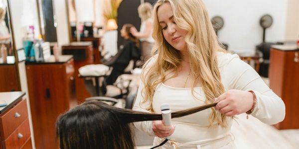 Stylist straightening client's hair in a salon.