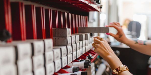 Hands selecting a box from a shelf filled with organized boxes in a salon.