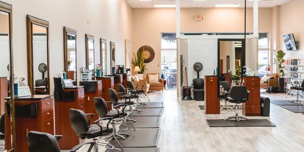Modern hair salon with multiple styling stations and black chairs.