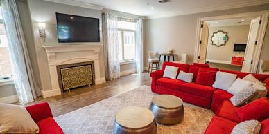 Bright living room with red sofas and a fireplace under a wall-mounted TV.