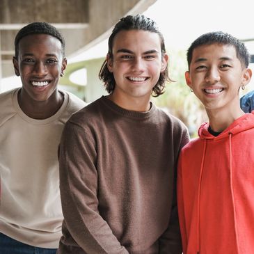 A group of five diverse young men smiling together outdoors.