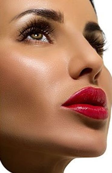 Woman applying makeup with bright red lipstick on her lips