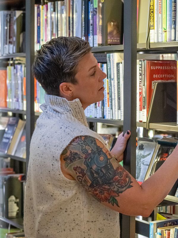 Lindsay (Simons) Troy, LCSW looking at books in a library. 