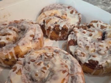 Four cinnamon rolls with icing in a box.