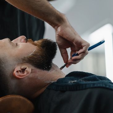 A man getting a straight razor shave at a barbershop.