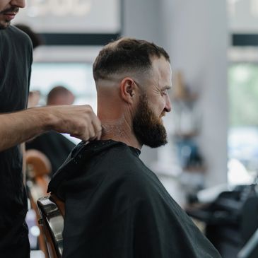 Man getting a haircut at a barbershop, smiling during the process.