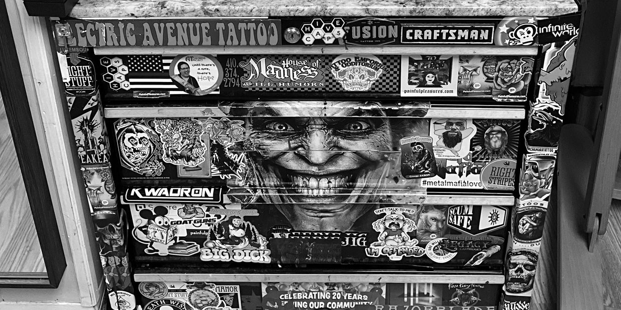 A sticker-covered toolbox with a Joker face sticker in the center.
