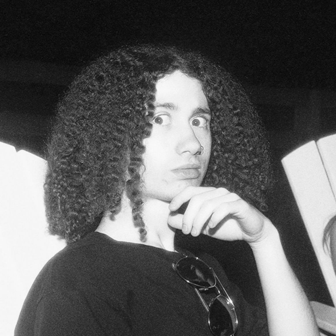 Person with curly hair and a nose ring looking surprised.