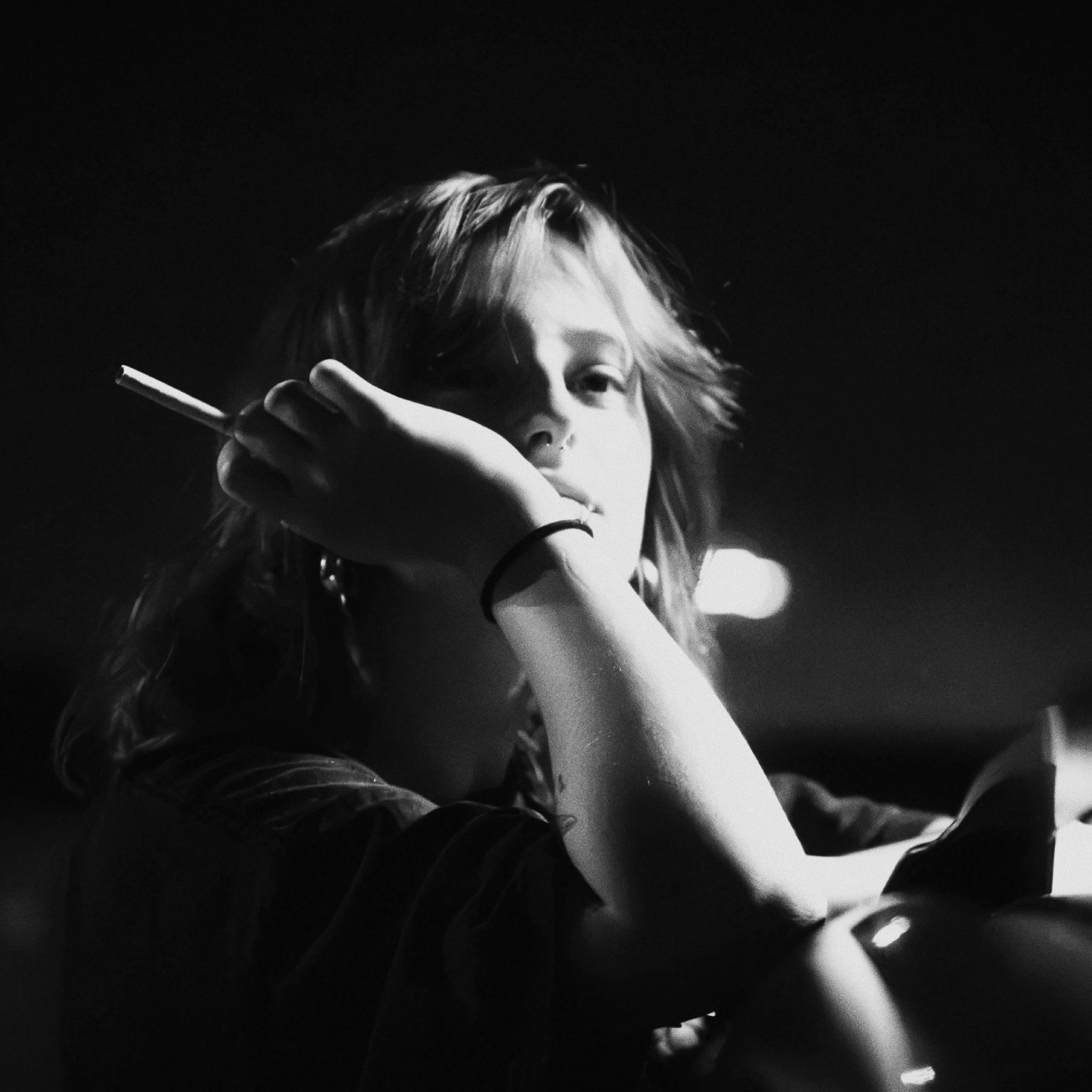 Black and white portrait of a person holding a cigarette.