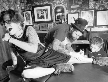 DYLAN SLAGLE/STAFF PHOTOS Timothy Heinbuch reacts as his 6 yr old son, Hunter, tattoos leg