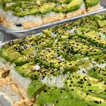 Sliced avocado sushi topped with sesame seeds.