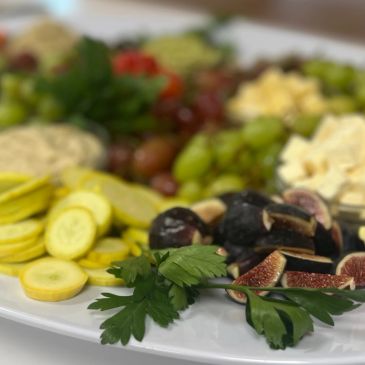 Close-up of a colorful appetizer platter with figs, squash slices, and parsley.