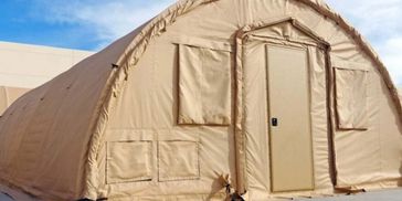 A large beige fabric tent with a door and windows set up outdoors.