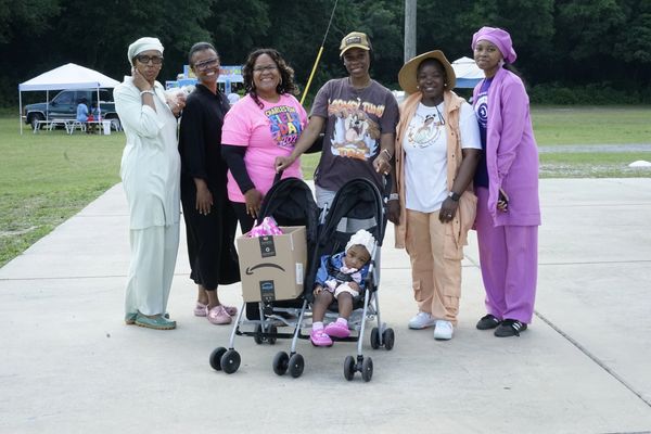 Group of women posing outdoors with a baby in a stroller.