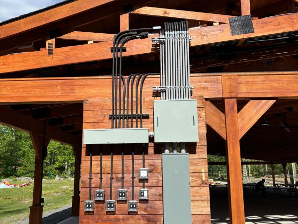 Electrical conduits and boxes mounted on a wooden structure.