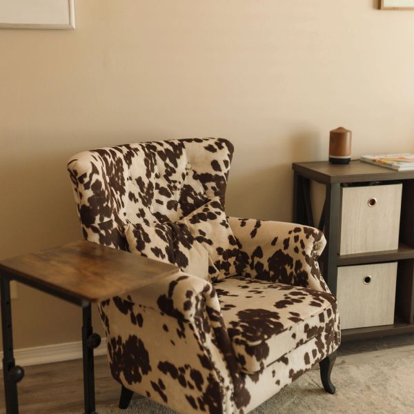 Cow print armchair with side table and storage unit.