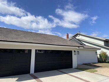 Modern home with white exterior paint wood panel siding, black sconces, and dark flat tile roof.