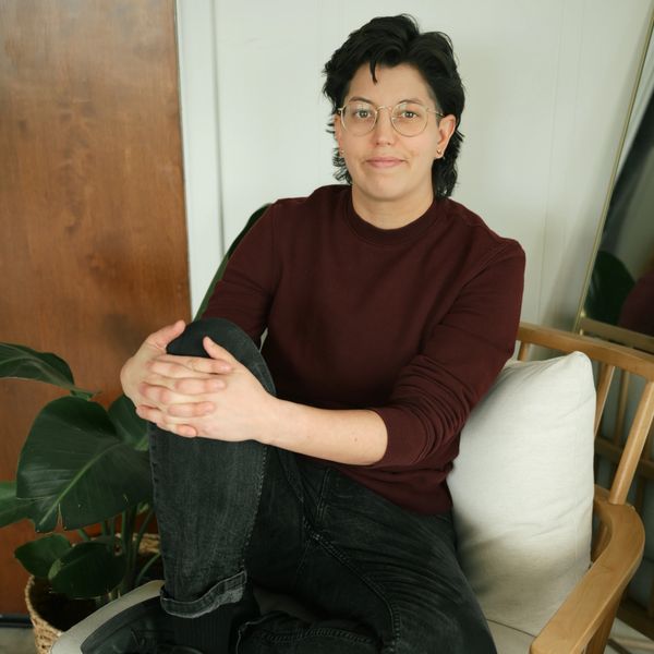 Person sitting on a chair with a relaxed smile.
