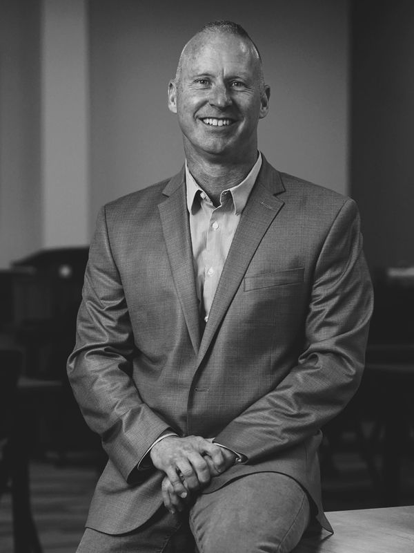 Smiling man in a suit sitting confidently indoors.