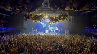 A large crowd enjoying a live concert with balloons falling from above.