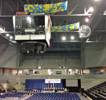 Indoor stadium setup with balloons and stage for an event.