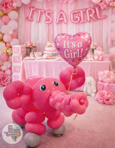 Pink balloon elephant holding a heart-shaped "It's a Girl" balloon at a baby shower.