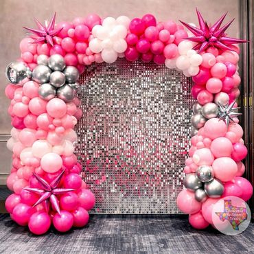 Colorful pink balloon arch with metallic star-shaped balloons and silver clusters.