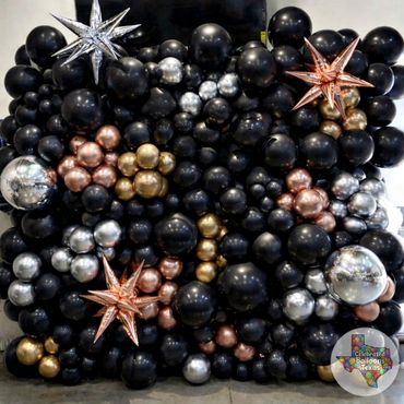 Elegant balloon wall with black, gold, silver, and rose gold balloons accented by star-shaped balloons.