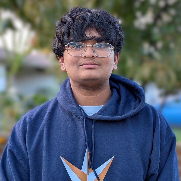 Young man wearing glasses and a blue hoodie outdoors.
