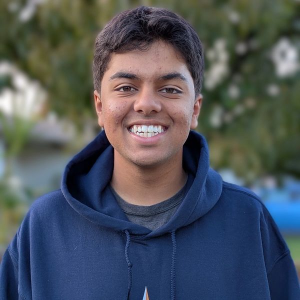 Smiling young man in a blue hoodie outdoors.