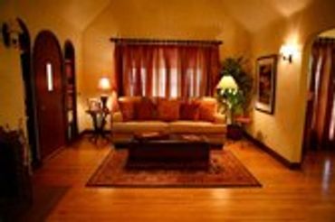 Bedroom with warm lighting, a large bed with red pillows, and a window