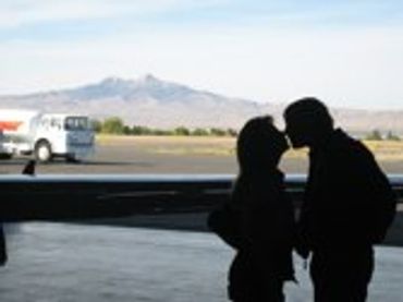 Two people silhouetted, kissing outdoors at sunset