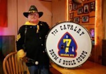 Man in uniform next to a drum with "THE CAVALRY" on it.