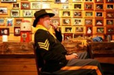 Man in uniform reading in a room with framed photos