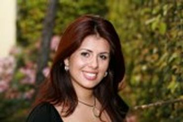 Woman with long dark hair smiling slightly