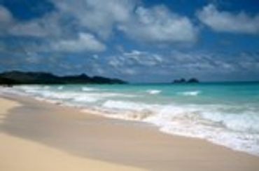 Tropical beach with white sand, turquoise water, and lush green hills
