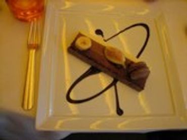 Dessert on a white plate with chocolate sauce swirls.