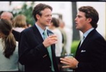 Two men in suits talking at an event.