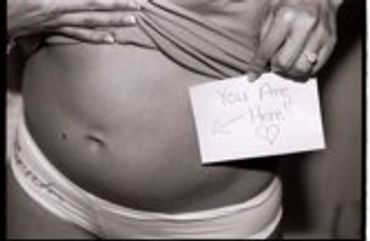 Pregnant belly with a small white card on it.