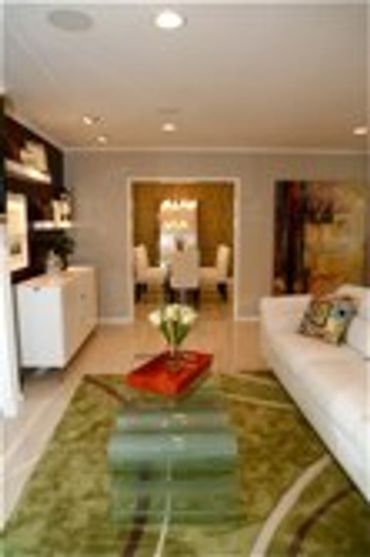 Living room with a green rug, white sofa, and red accent cushions