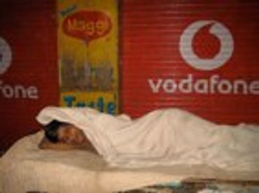 Person sleeping on a red mat with a Vodafone sign.