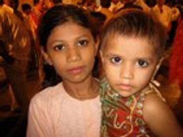 Two young girls, one looking at the camera, one at viewer.