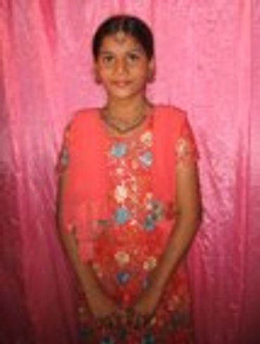 Young girl in a pink dress standing in front of a pink wall
