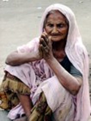Older woman with hands clasped, wearing a head covering