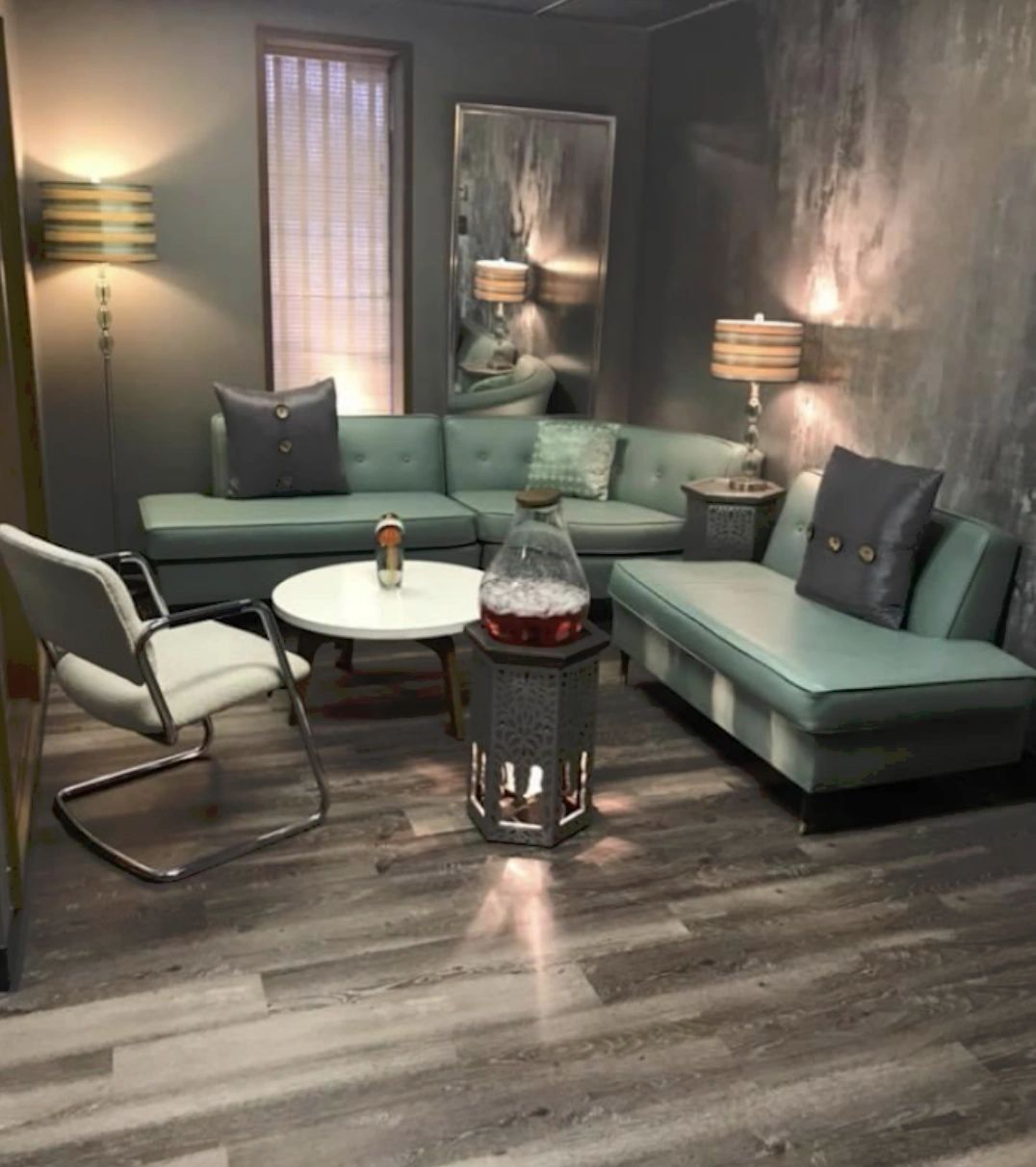 Modern reception room with teal couches and chrome furniture on planks of gray wood flooring