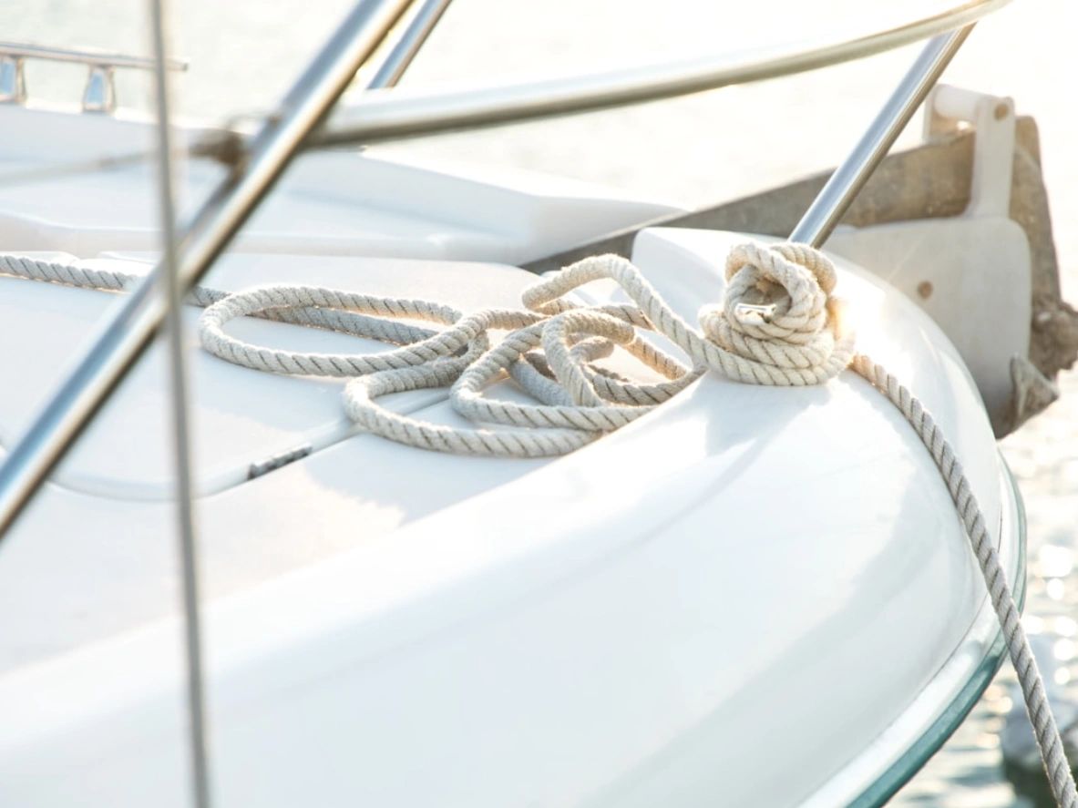 Coiled rope resting on a white boat deck near metal railings.