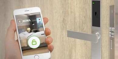 Smartphone unlocking a modern electronic door lock in a wooden door.