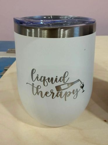 White tumbler with 'liquid therapy' text and wine glass design.