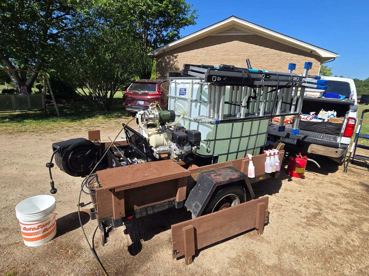 Trailer with water tanks, ladders, and cleaning supplies next to a pickup truck.