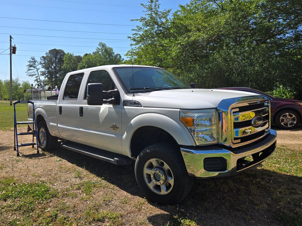White Ford pickup truck parked on grass with a Kobalt cart beside it.